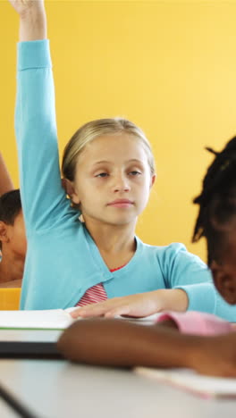 school kids raising hand in classroom