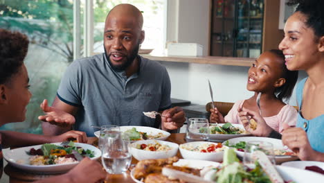 close up of family sitting around table at home enjoying meal together