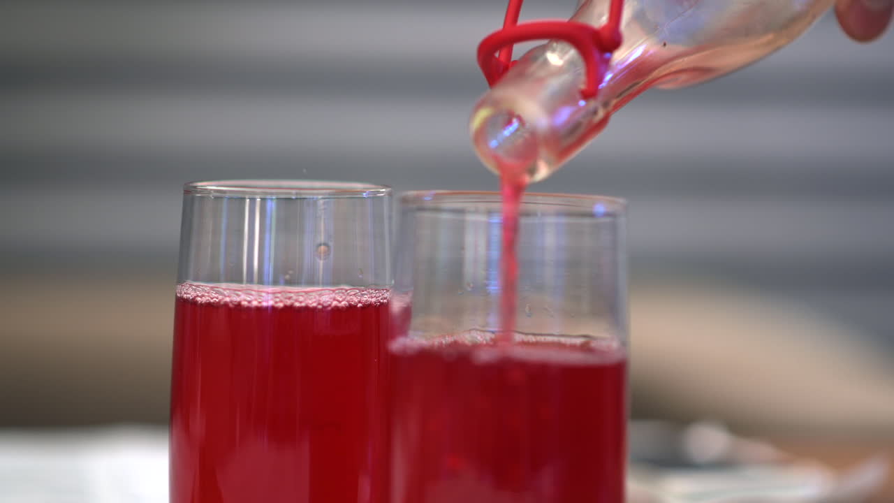 Waiter pouring red juice in glasses at a restaurant