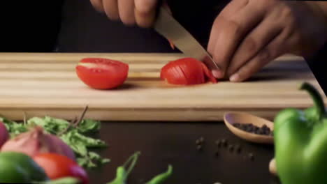 chopping tomato on a wooden chopping board with a sharp knife in the kitchen, cutting vegetables