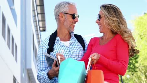 una pareja madura está mirando las bolsas y riendo después de comprar