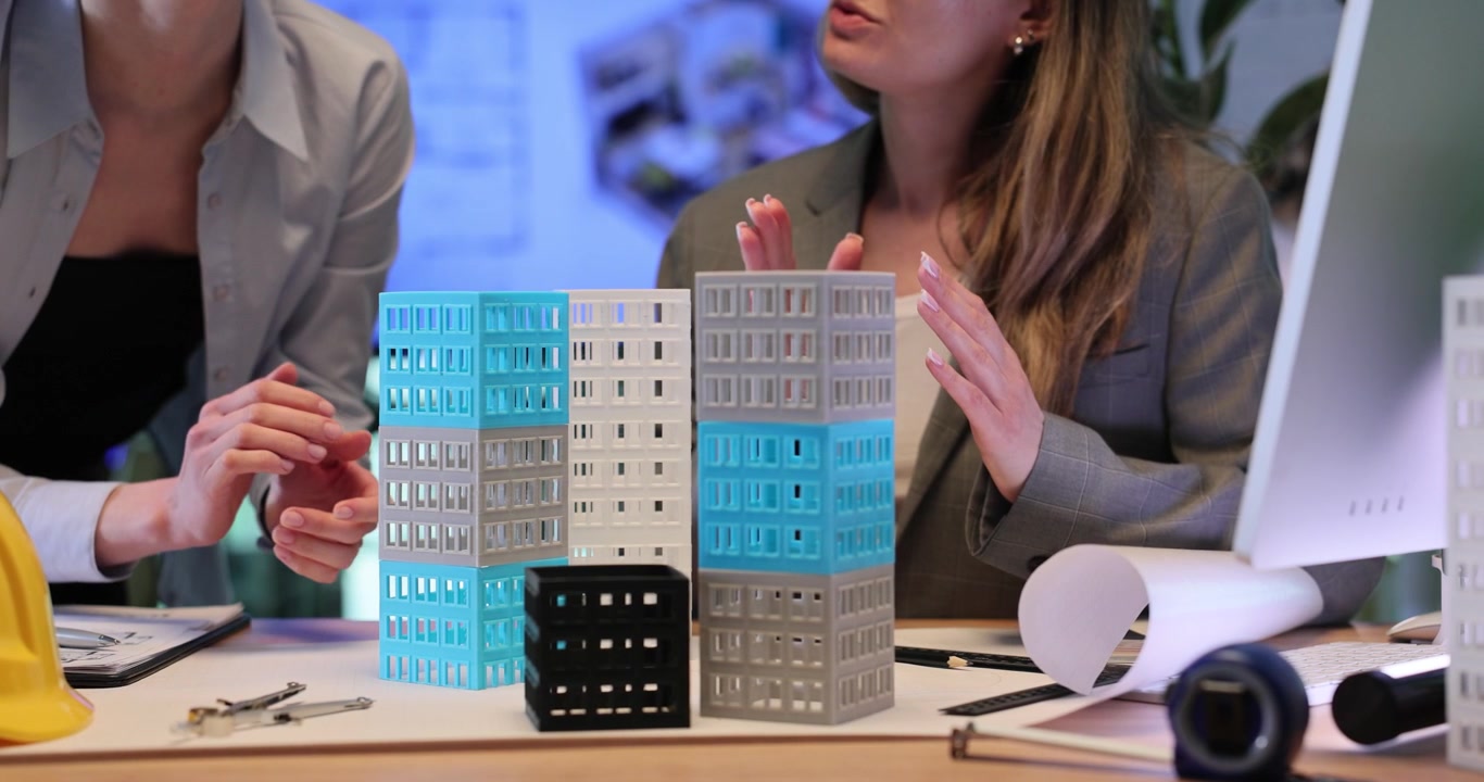 Women examine building models and analyze design details