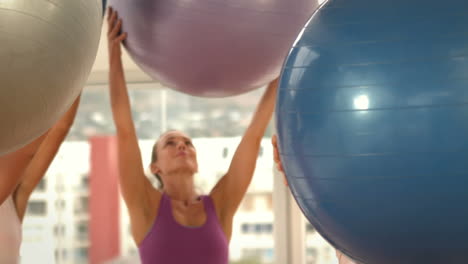 mujeres en forma levantando una pelota medicinal