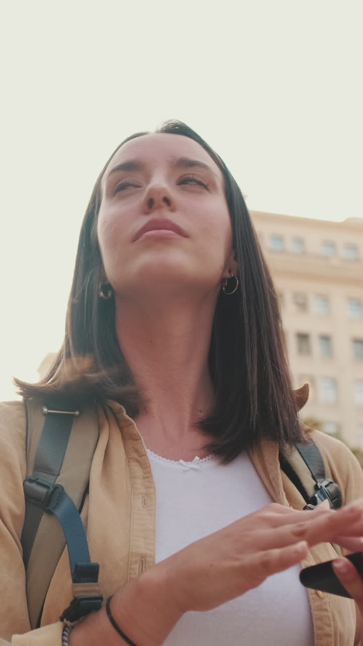 Giovane donna che usa lo smartphone e si guarda intorno in città