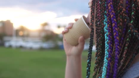 mujer con trenzas coloridas bebiendo café