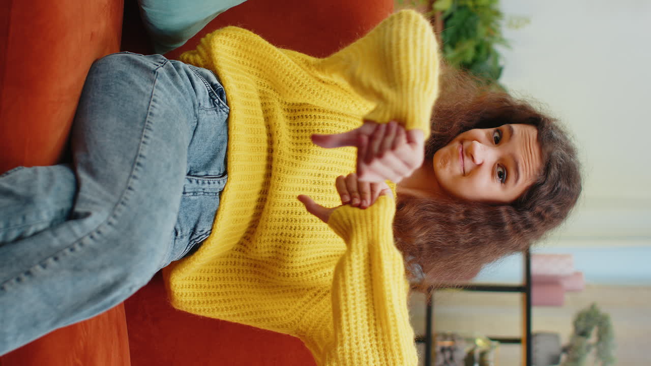 Upset teen girl showing thumbs down dislike bad work disapproval dissatisfied feedback at home