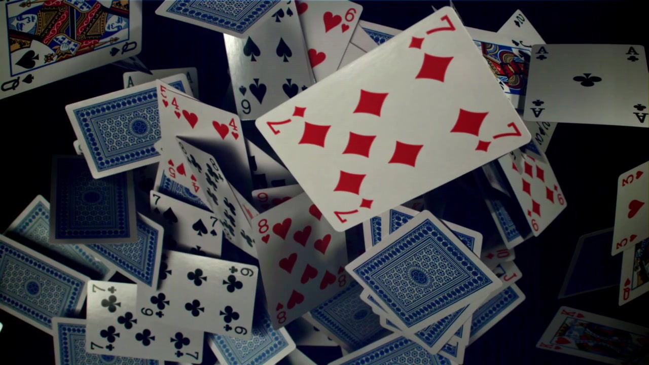 Playing Cards Falling and Scattering in Slow Motion on a Black Background