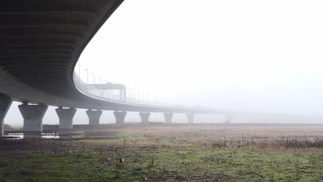 ghostly misty concrete support structure under motorway flyover slow left pan