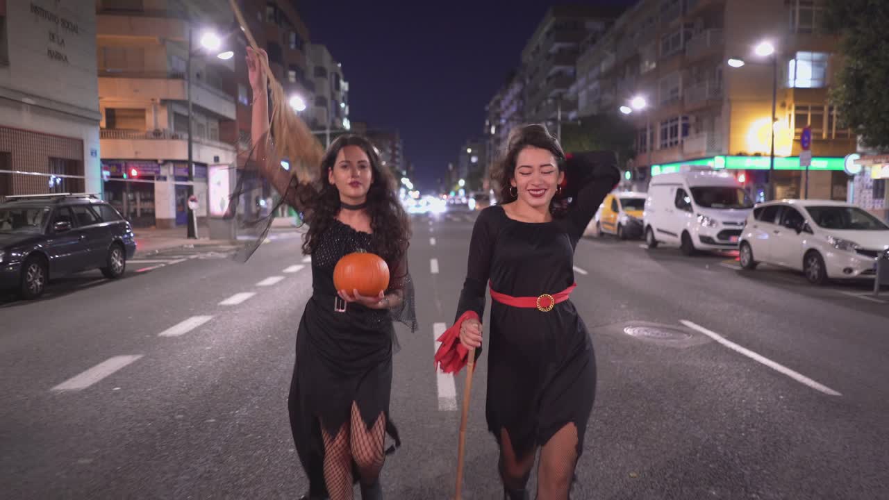 Two Friends in Halloween Costumes on a City Street at Night