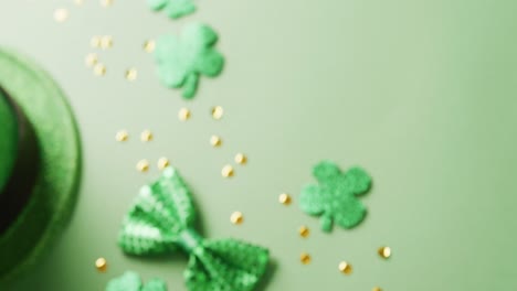 Video-of-saint-patricks-day-green-shamrock,-hat-and-bow-tie-with-copy-space-on-green-background