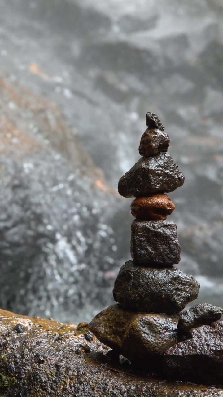 Pila di pietre in equilibrio davanti a una cascata impetuosa