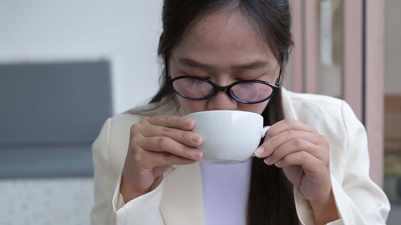 Young businesswoman smiling and drinking hot mocha in coffee shop during day pedestal shot