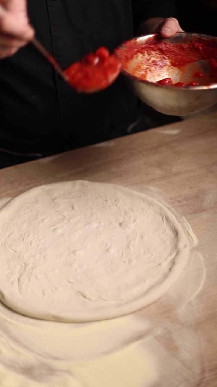 Chef che prepara la salsa per pizza sull'impasto
