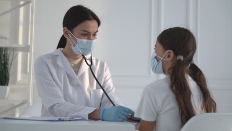 female doctor listening to little girl with stethoscope. woman examining patient.