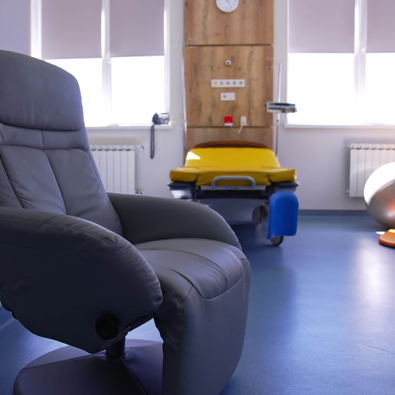 Cozy grey armchair with moving footrest for women in labor. New modern pieces of furniture in the maternity hospital ward