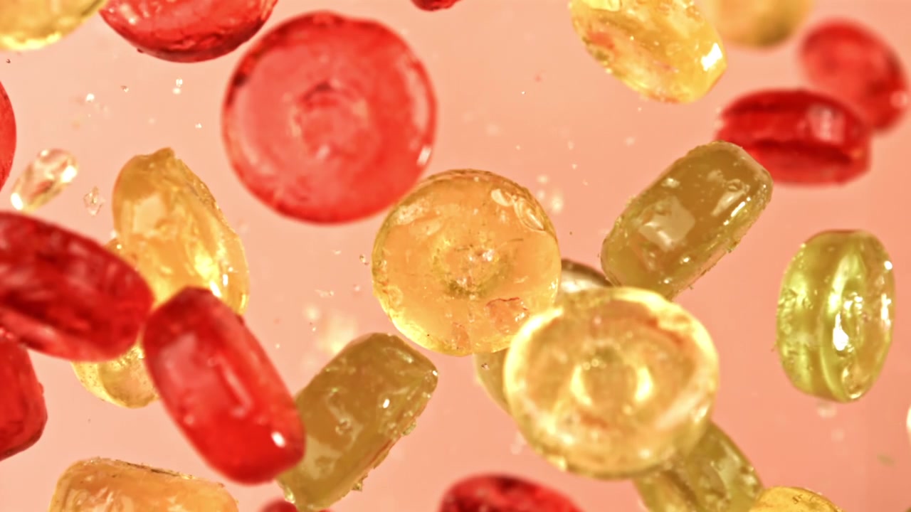 Caramelle colorate che galleggiano al rallentatore con goccioline d'acqua