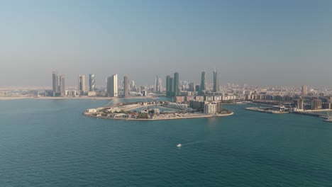 aerial view over reef island towards downtown manama and skyscrapers, bahrain. wide angle drone shot sunny day