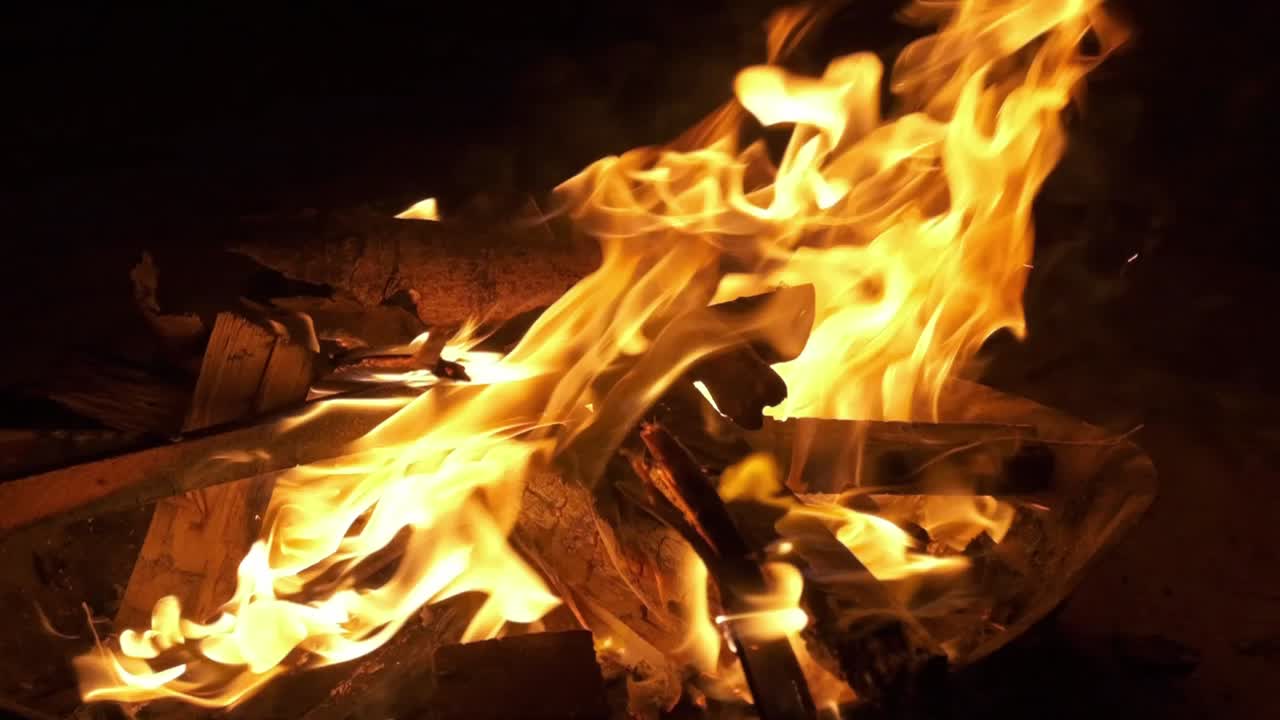 camera slow zoom in on camp fire flames with black background shot in slow motion