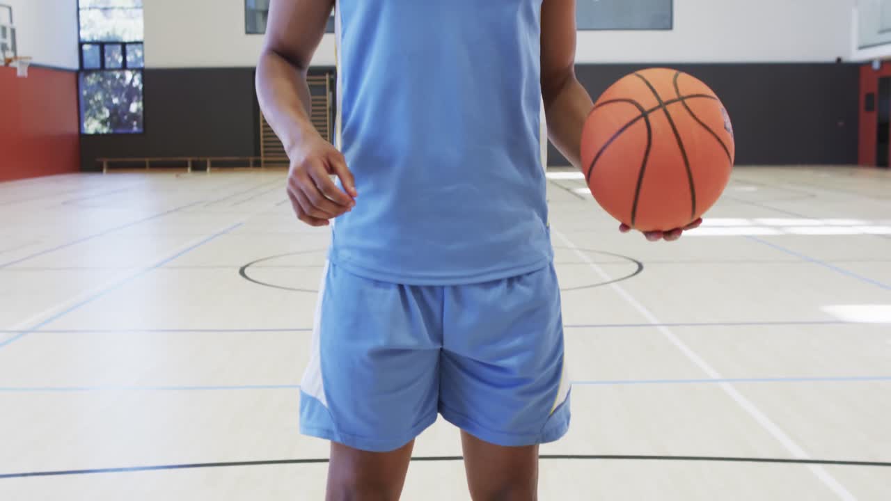 primer plano de un jugador de baloncesto afroamericano disparando pelota en una cancha cubierta, cámara lenta