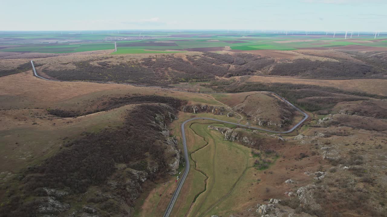 извилистая дорога через ущелья доброгея, окруженная холмистыми холмами и обширным открытым ландшафтом.