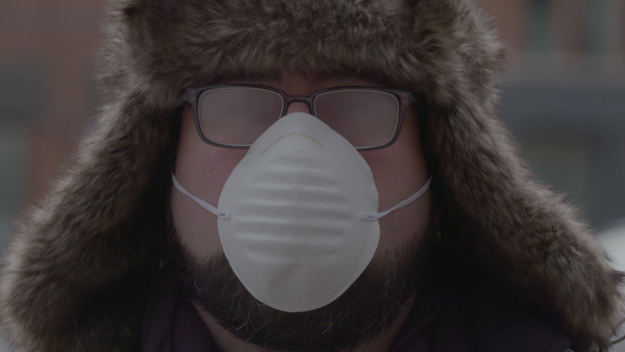 retrato de un hombre con una máscara facial, sombrero de trampero y anteojos empañados