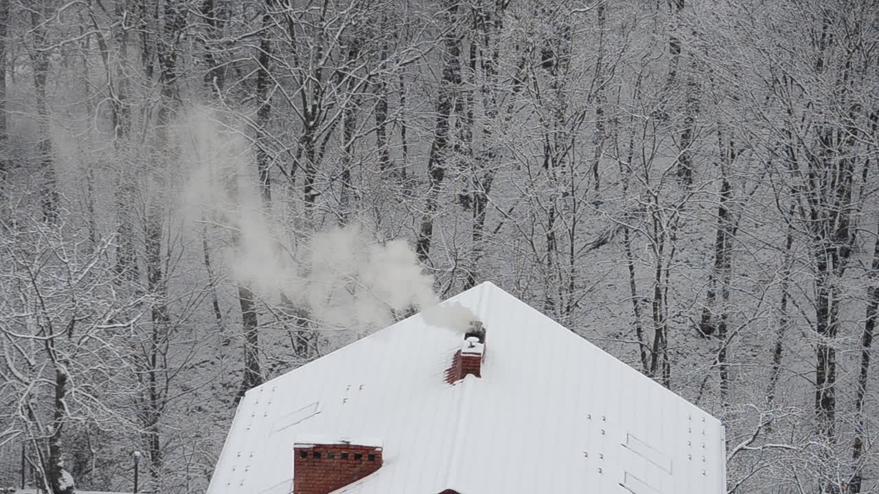 Røg fra skorstenen på en snebaggrund.