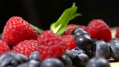 mixed fresh berries. blueberries and raspberries with mint on wooden background rotations. close up. 4k