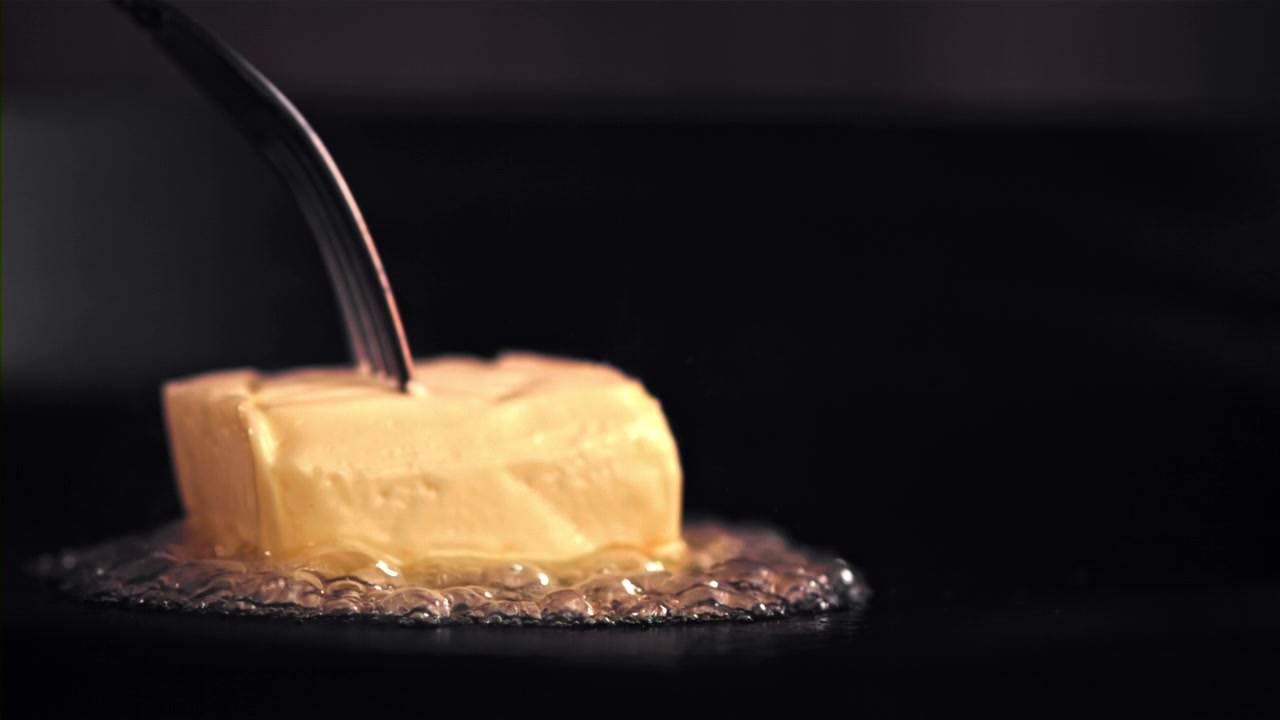 Block of Butter Melting in a Hot Pan with a Fork