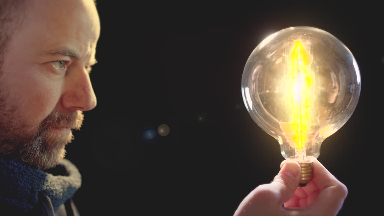 el hombre sostiene una gran bombilla vieja en la mano y se enciende