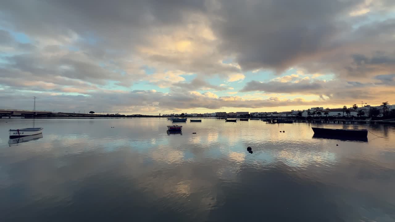 스페인 안달루시아의 바르바테에 있는 강의 조용한 물을 비추는 놀라운 일출, 작은 어선들이 부드럽게 흔들리고, 그 반사들이 그림 같은 장면을 만니다.