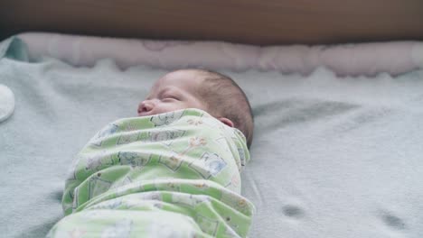 bebé recién nacido con los ojos cerrados y el cabello claro se encuentra en pañuelo