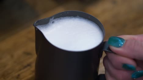 leche al vapor y espumosa lista para verter café en el café, primer plano