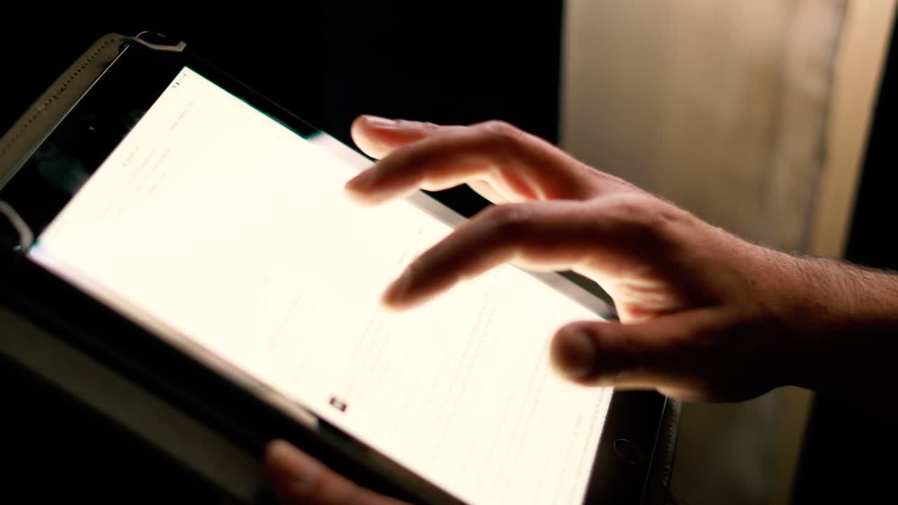 filmado en cámara lenta mostrando las manos del hombre navegando en las redes sociales o jugando con una tableta móvil por la noche