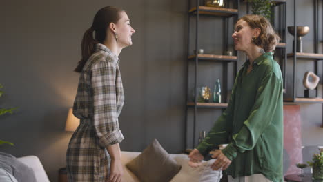 two sisters hugging each other at home and then smiling at camera