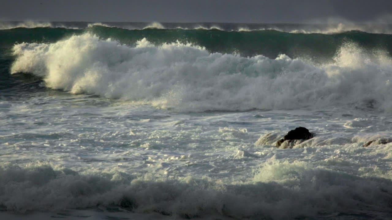grandes olas llegan a una playa después de una gran tormenta en cámara lenta