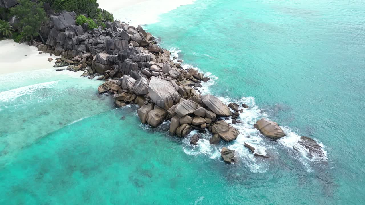 La Digue Island, Seychelles archipelago , drone approaching secluded lonely tropical white sand beach waves crashing in to rock , travel paradise destination