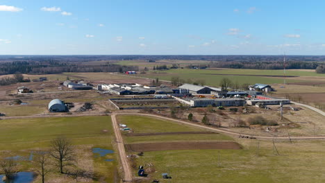 aerial view of modern farming buildings in rural lithuania, landscape and blue skyline on sunny day, drone shot