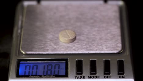 pill being weighed on a digital scale