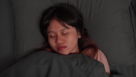 sleeping woman, peaceful, calm expression, resting in cozy bed under gray blankets