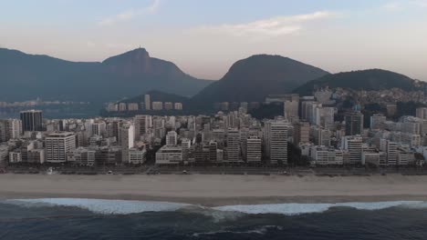 vista aérea de la playa vacía de ipanema con el lago de la ciudad y la montaña corcovado en río de janeiro al fondo en un amanecer colorido y nebuloso