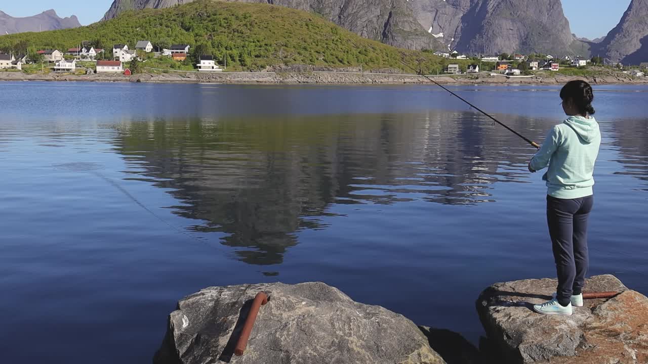 Pesca della donna sulla filatura della canna da pesca in Norvegia.