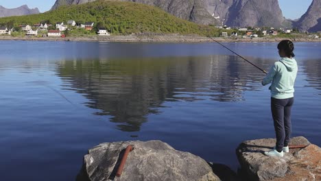 woman fishing on fishing rod spinning in norway.