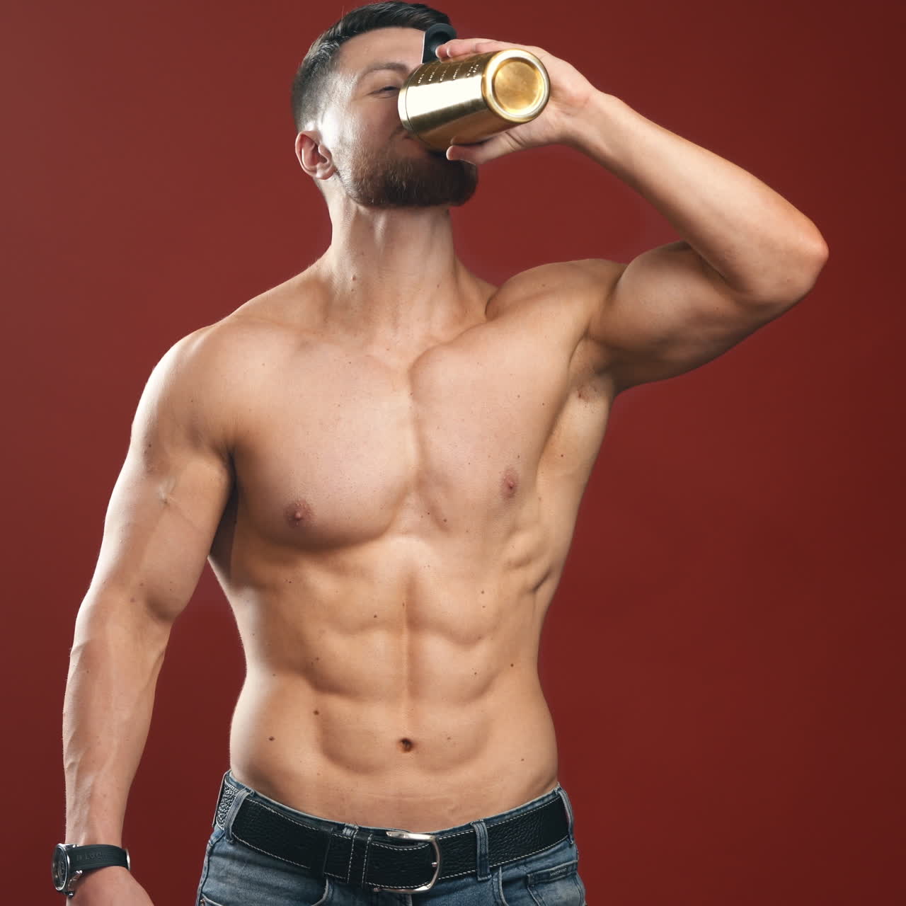 Very muscular sporty guy drinking protein in dark red background with naked torso. Athletic body. Sport and sport nutrition concept video.