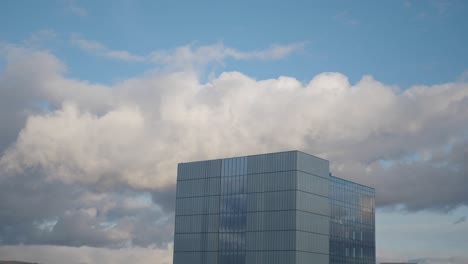 modern glass office building under a cloudy sky