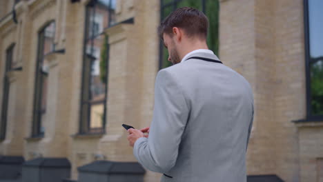 back view businessman using mobile phone. stylish man looking cellphone screen.