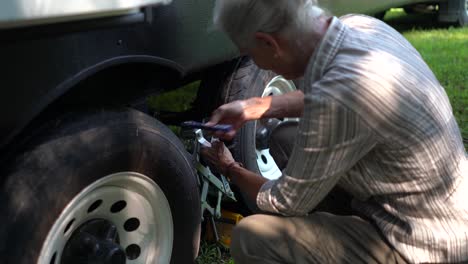 Closeup-of-elderly-woman-unscrewing-a-tire-locking-chock-on-an-RV