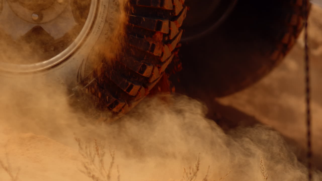 primer plano de la rueda del coche pateando nubes de polvo movimiento lento y arena en pendiente