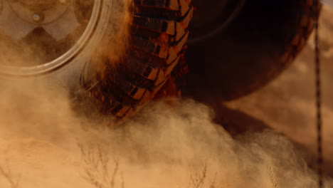 closeup of car wheel kicking up clouds of dust slow motion and sand going slope