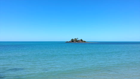 aerial: drone flying towards a small remote island out to sea, in tropical queensland, australia