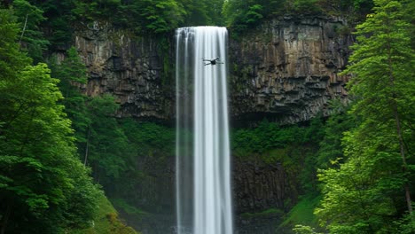 captivating aerial view of a majestic waterfall surrounded by lush green forests, showcasing the beauty of nature and the power of water with a drone capturing the scene
